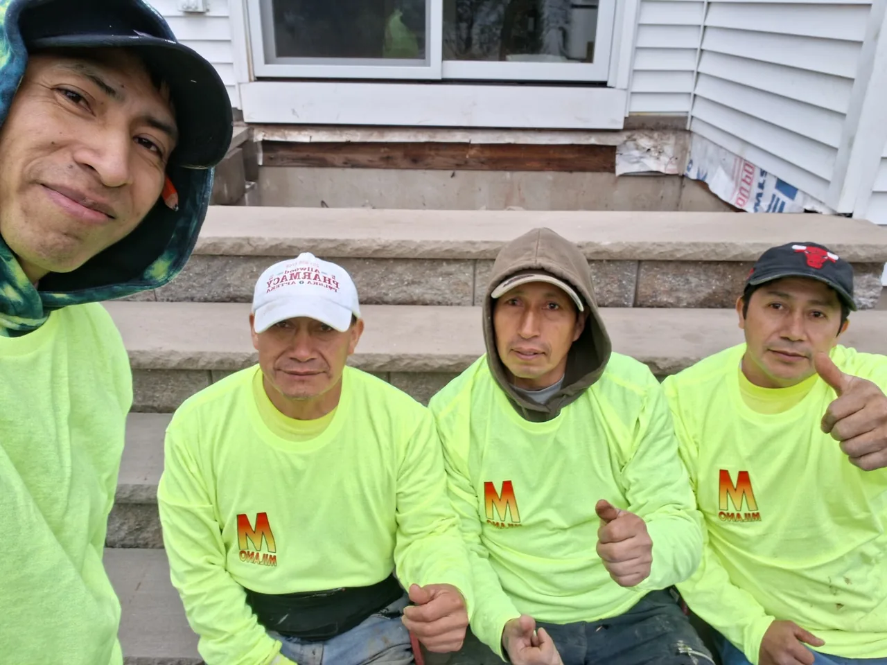 Four crew members in lime green shirts smiling.