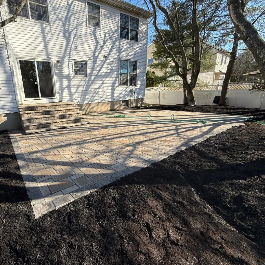 Newly installed paver patio with stairs behind house.