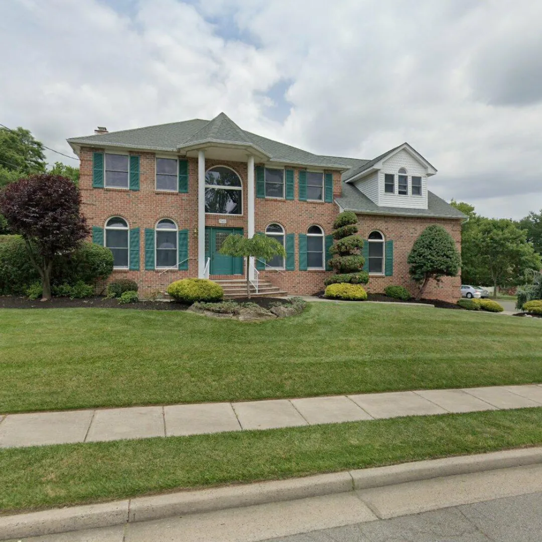 Large brick house with manicured lawn and landscaping.