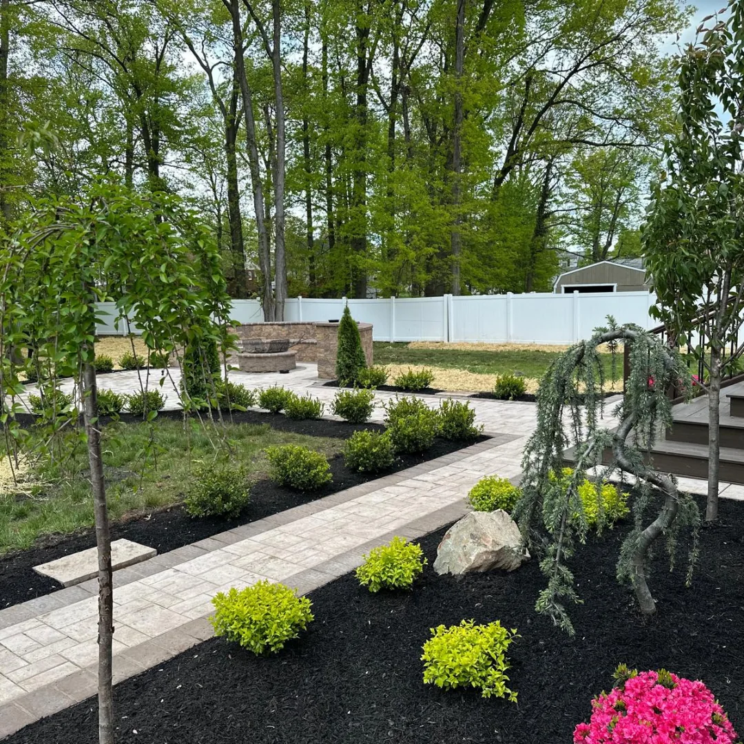 Beautiful backyard landscaping with pavers, fire pit, and plantings.
